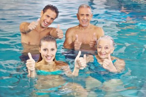 Happy group with senior couple in water holding their thumbs up